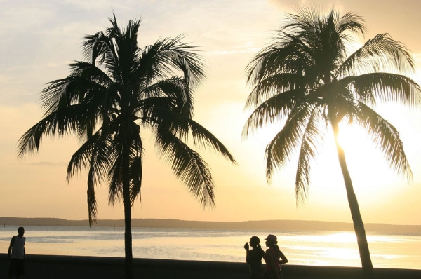 Hoàng hôn in bóng những người đi dạo trên bãi biển thành phố Cienfuego.